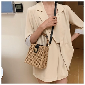 Detail of woven straw texture with elegant bamboo handle and black leather flap closure