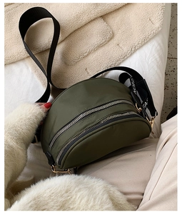 Close-up of olive green nylon crescent bag with double zippers and wide logo strap