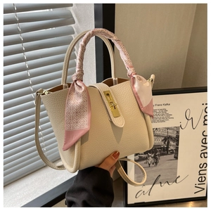 Close-up of cream leather bucket bag with gold twist lock and silk scarf detail