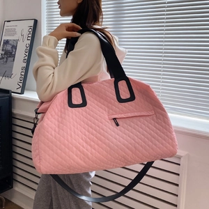 Pink quilted travel bag with black shoulder straps and spacious interior design