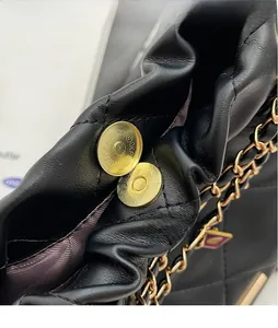 Détail du fermoir magnétique doré texturé sur le sac seau en cuir noir matelassé