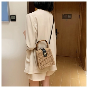Detail of hand-woven straw crossbody bag with bamboo handle and black leather flap