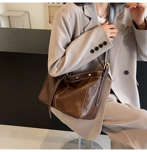Detail of dark brown tote bag showing oily leather texture and white contrast stitching