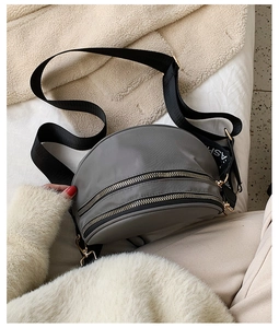 Detailed view of gray nylon crescent bag with gold zippers and FASHION logo strap