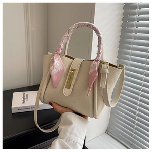 Detail of creamy white pebble leather handbag with metal twist lock and pink silk scarf wrap
