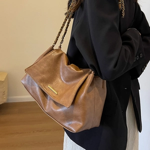 Sac fourre-tout vintage marron avec chaîne dorée porté par un modèle en intérieur