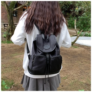 Detail of the black nylon backpack showing the flap cover and its circular AMAI logo