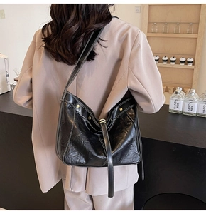 Detail of black leather hobo bag with contrast stitching and decorative metal rivets