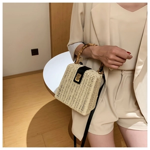 Close-up of handmade straw handbag featuring a bamboo handle and golden metal twist lock