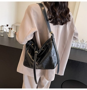 Detail of black leather tote bag featuring white contrast stitching and adjustable strap
