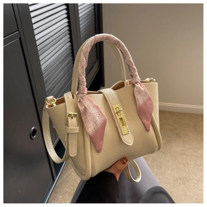 Detail of lychee pattern leather bucket bag with gold clasp and silk scarf handle