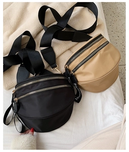 Detail of black and khaki nylon crescent crossbody bags with double zippers and webbing