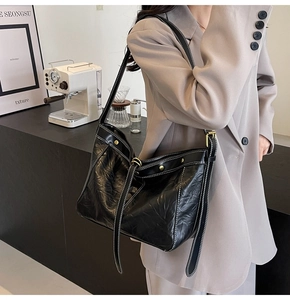 Detail of black tote bag with white contrast stitching and pleated texture on shoulder strap