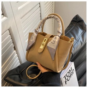 Close-up of light brown lychee grain handbag with silk scarf wrap and gold twist lock