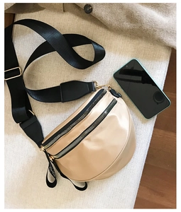 Detailed macro view of beige nylon crescent bag featuring shiny golden dual zippers