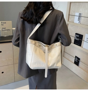 Detail of off-white tote bag featuring pleated texture and gold rivet embellishments