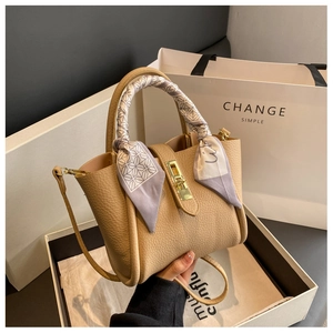 Detail of khaki lychee leather bucket bag with silk scarf handle and gold twist lock