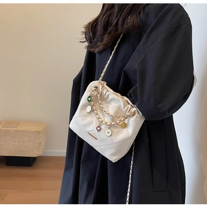 Détail du sac seau blanc matelassé avec chaîne dorée et charms de coeurs colorés