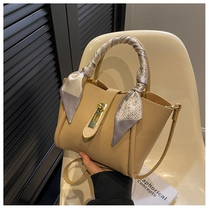 Detail of light brown lychee leather bucket bag with silk scarf handle and gold buckle