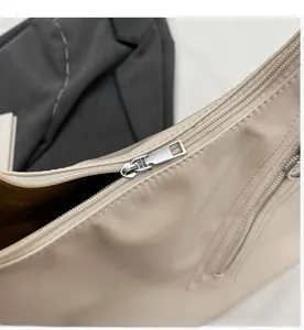 Detail of a smooth silver metal zipper on an off-white soft leather tote handbag