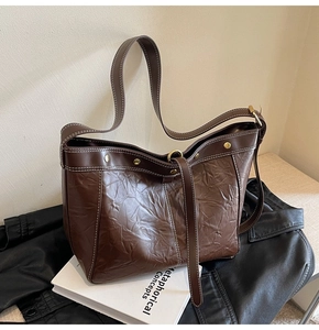Close-up of deep brown tote bag with oily leather texture and white contrast stitching