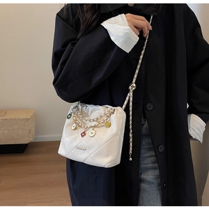 Détail du sac bandoulière matelassé avec pendentifs en émail coloré et chaîne
