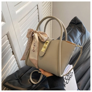 Detail of grey lychee leather bucket bag with gold clasp and floral scarf handle wrap