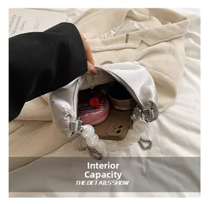 Detail showing inner capacity of white satin cloud bag with pearl handle and embroidery