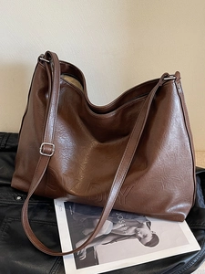 Close-up of coffee brown tote bag with retro leather texture and embossed logo