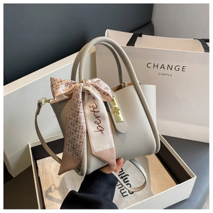 Detail of grey pebble leather bucket bag with gold lock and decorative silk scarf in box