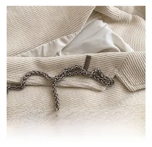 Detail of off-white corduroy fabric texture and decorative silver woven chain strap
