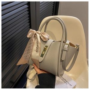 Close-up of grey litchi grain leather bucket bag with silk scarf on a chair