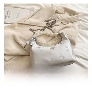 Detail of silver floral jacquard fabric and white pearl handle on this moon bag