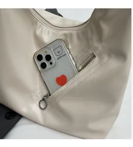 Detail of a beige PU leather tote showing a functional side zipper pocket with a smartphone
