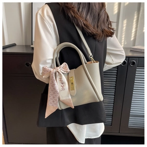 Close-up of gray lychee leather handbag featuring a metal lock and floral silk scarf detail
