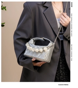Detail van zilveren mini-tas met kreukeltextuur, grote parels en metalen kettingriem