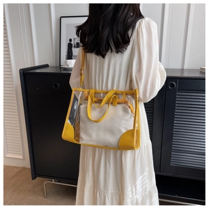 Detail of transparent PVC tote bag with yellow leather trim and inner pouch on model
