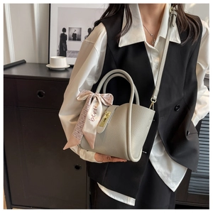 Close-up of grey leather bucket bag with silk scarf detail and golden metal lock