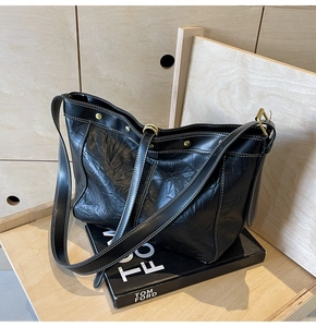 Detail of black tote bag with white contrast stitching and gold metal hardware