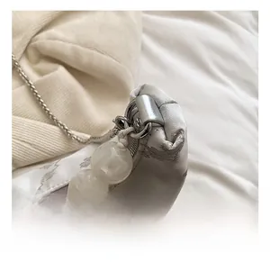 Close-up of silver satin bag with floral jacquard and large marble texture decorative bead
