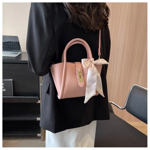 Pink lychee grain leather bucket bag with decorative scarf shown in an office setting