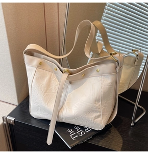 Detailed shot of white tote bag with textured crinkled leather and gold hardware accents