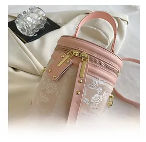 Detail of pink leather bucket bag with floral embroidery and smooth gold dual zippers