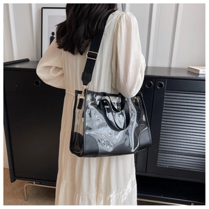 Detail of transparent PVC tote bag with black faux leather trim and golden metal hardware