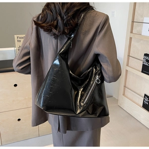 Detail of glossy black patent leather tote bag with stylish side zipper and wide shoulder strap