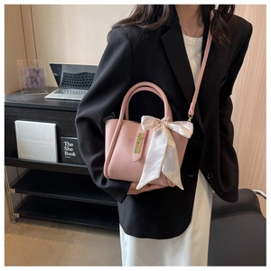 Pink lychee texture bucket bag with metal buckle and silk ribbon accessory on a model