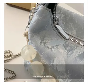 Detailopname van marmeren textuur tas met gladde metalen rits en zilveren kettingdetail