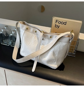 Close-up of cream textured leather tote bag with elegant gold hardware and wide shoulder strap