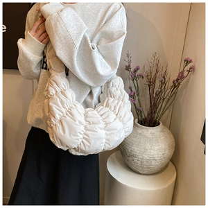Detailansicht der weißen gesteppten Croissant-Tasche mit weichen Falten und Textur