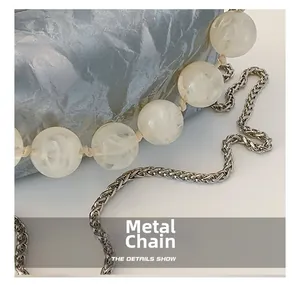 Macro detail van marmeren kralen en zilveren metalen ketting aan een moderne ketting